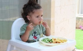 bambina mangia del cibo sul seggiolone